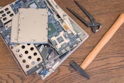 Bad computer repair, broken old computer or laptop with hammer and pliers.