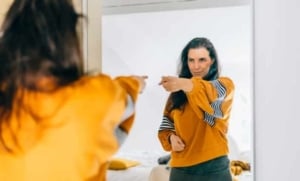 woman in front of a mirror pointing at herself
